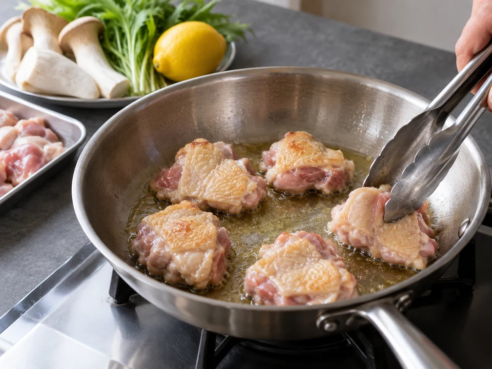 鶏肉のクリーム・スパゲッティー：鶏もも肉の皮目をフライパンで焼く手元。