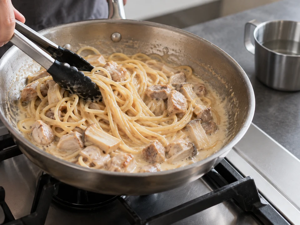 鶏肉のクリーム・スパゲッティー：鶏肉入りクリームソースをフライパンで煮詰める手元。