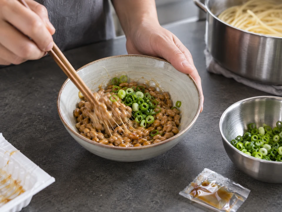 納豆のスパゲッティー：たれと小ねぎを加えた納豆を粘りが出るまで混ぜる手元。